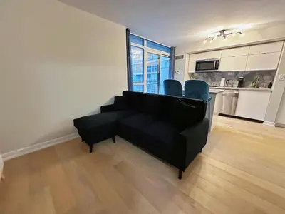 a living room with a black couch and blue chairs at Downtown 2 bedroom Gem with Free Parking in Toronto