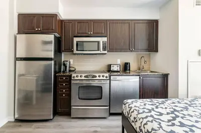a kitchen with stainless steel appliances and wooden cabinets at Luxury Suites Steps to CN Tower - Lock in 4 Weeks Enjoy Half OFF in Toronto