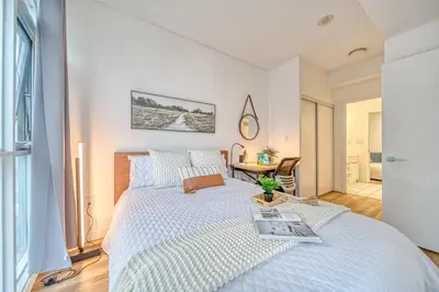 a bedroom with a white bed and a table at The Snug 1plus1 Suite with Free Parking in Toronto