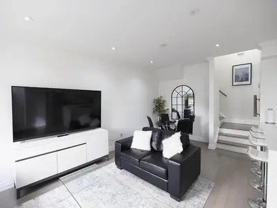 a living room with a black couch and a large television at Executive 3 Bedroom Town House in Mississauga