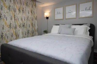 a bedroom with a large white bed with two pictures on the wall at French Charm in Brampton 2 Bdrm Apt in Brampton