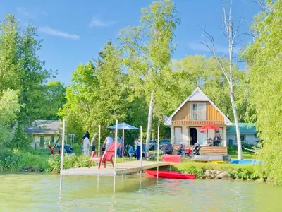 a house on a dock in the water with people at Charming Winter Cottage Retreat with Scenic Snow Views in Colborne