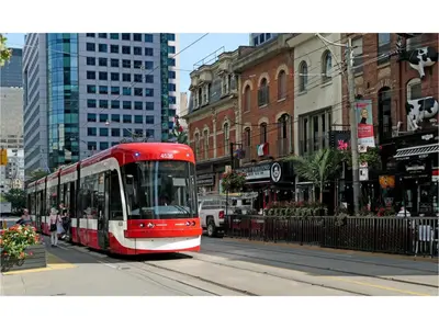 a red and white bus driving down a city street at Lovely Leslieville, exploring nature in the city in Toronto
