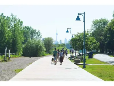 a group of people walking their dog on a sidewalk at Lovely Leslieville, exploring nature in the city in Toronto