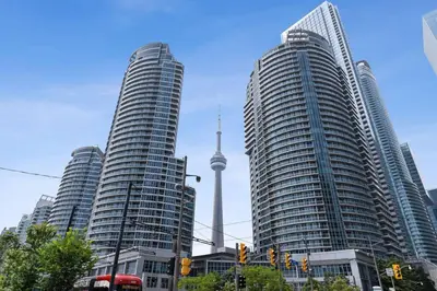 two tall buildings in a city with a tv tower at Toronto Views ~ Pool ~ BBQ ~ Harbourfront ~ WIFI in Toronto