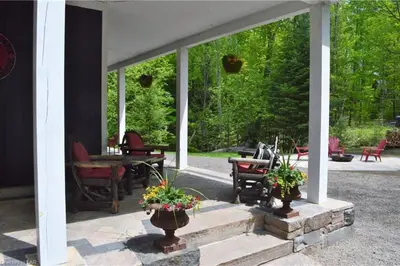 a screened in porch with chairs and flowers in vases at The Hidden Porch at Sir Sam's (hot tub & sauna) in Haliburton