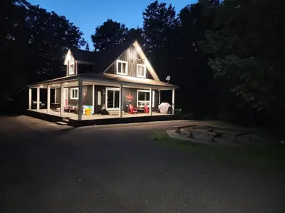 a large white house with a lot of windows at The Hidden Porch at Sir Sam's (hot tub & sauna) in Haliburton