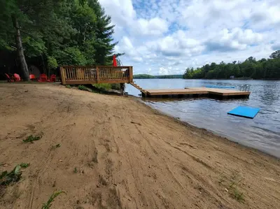 a dock on a lake with a person standing on it at Red Cedar Chalet on Brady Lake in Hindon Hill