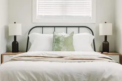 a bed with white sheets and pillows and two lamps at Woodland Chase in Wellington
