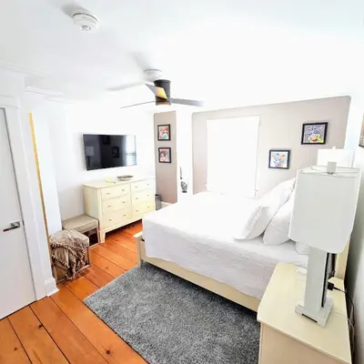 a white bedroom with a bed and a television at The Royal Manor Inn in Niagara on the Lake