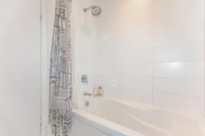 a white bathroom with a tub and a shower curtain at SkyHigh Haven LED-Lit Downtown Condo Retreat in Toronto