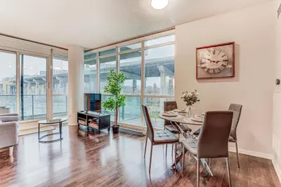 a dining room with a table and chairs and a clock at Prime City Pad 2 Bedroom with CN Tower View in Toronto