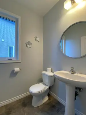 a bathroom with a toilet and a sink and a mirror at Stylish 3 Bdrm house- king bed, Netflix, parking in Kitchener