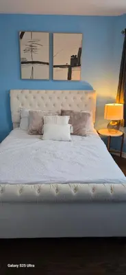 a bedroom with a white bed with two pictures on the wall at short time rental in Kawartha Lakes