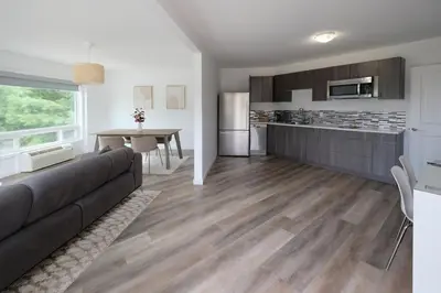 a living room with a couch and a kitchen at Stay Inn Muskoka in Gravenhurst