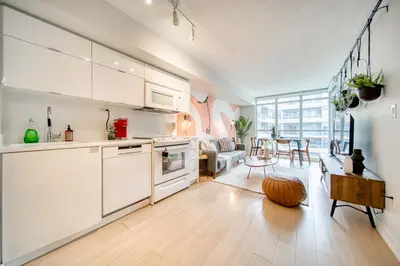 a kitchen with white cabinets and a living room at Stylish Downtown Toronto Suite with Free Parking in Toronto