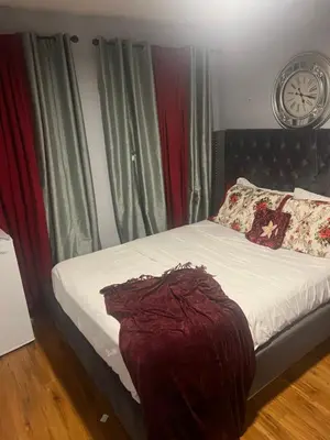 a bed in a room with a clock on the wall at Queen’s Gate Ecstasy Home in Brampton