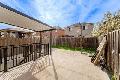 a patio with a fence and a basketball hoop at Lovely Cozy Apartment in Brampton