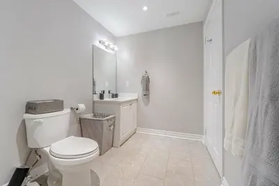 a white bathroom with a toilet and a sink at Lovely Cozy Apartment in Brampton