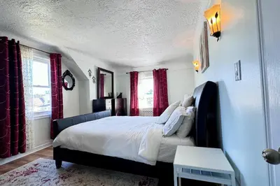a bedroom with a large bed with red curtains at Near the Falls Two Bedroom - 5 min Walk to Clifton in Niagara Falls