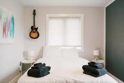 a bedroom with a bed with a guitar on the wall at Sandbanks Cottage on Sheba's Island - 5 min drive, pet friendly in West Lake