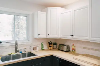 a kitchen with white cabinets and a sink and a window at Sandbanks Cottage on Sheba's Island - 5 min drive, pet friendly in West Lake