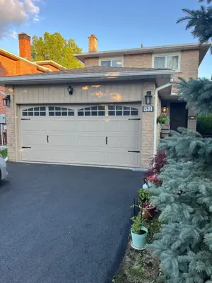 a house with a white garage door and a tree at cozy private guest suite in Richmond Hill