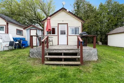 a house with a deck with a table and an umbrella at Enjoy Relax at Rice Lakes in Bailieboro