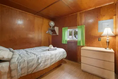 a bedroom with a bed and a dresser with green curtains at Enjoy The Outdoors at Rice Lakes in Bailieboro