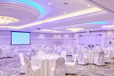 a banquet hall with white tables and chairs and a screen at Staybridge Suites St. Catharines Conf Ctr by IHG in St. Catharines