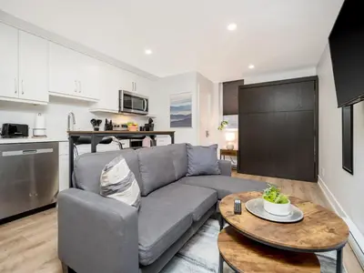 a living room with a gray couch and a table at Cozy Studio Apt - Corktown Hamilton - Near DT in Hamilton