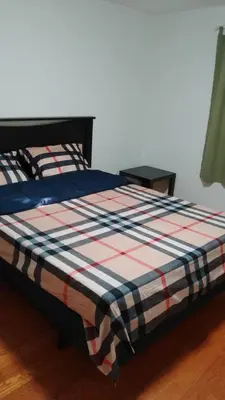 a bed with a checkered blanket on top of it at Bishop in Mississauga
