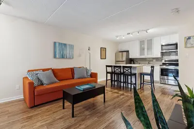 a living room with an orange couch and a kitchen at Whispering Pines Escape in Collingwood