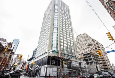 a tall building on a city street with cars at Elegant 2BR & 2BA Retreat in Prime Yorkville, Downtown in Toronto