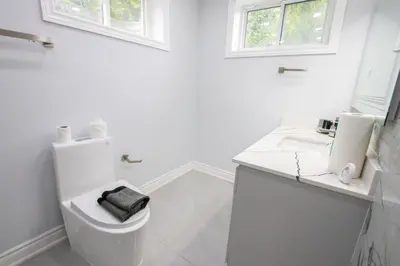 a white bathroom with a toilet and a sink at Deer Run Cottage- Golf Course cottage in Kawartha Lakes