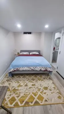 a bedroom with a bed and a rug on the floor at Moons & Noons -Separate Unit for your Comfort in Ajax