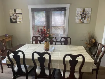 a dining room table with a vase of flowers on it at Exceptionally Close to the Falls Amazing Location & Complimentary Breakfast Delivered Daily to the Rental in Niagara Falls
