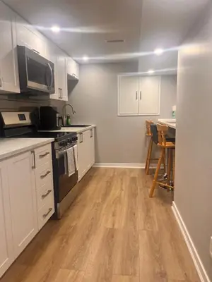 a kitchen with white cabinets and a table with chairs at Bowmanville basement apartment in Bowmanville
