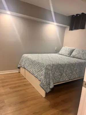 a bedroom with a bed and a wooden floor at Bowmanville basement apartment in Bowmanville