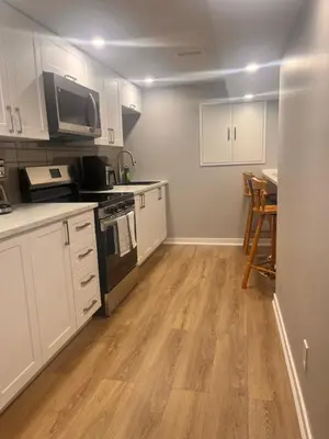 a kitchen with white cabinets and a table with chairs at Bowmanville basement apartment in Bowmanville