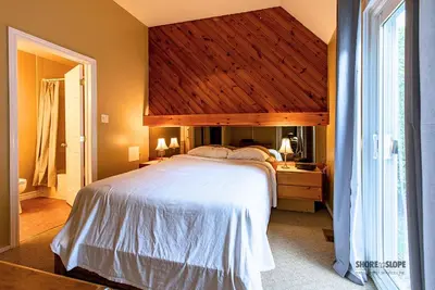 a bedroom with a large bed with a wooden ceiling at Mountain View Villas One Bed Loft Suite in Collingwood