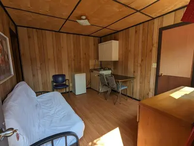 a small room with a bed and a table and chairs at Tiny Wood Cottage 05 in Wasaga Beach
