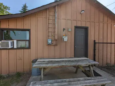 a picnic table in front of a building with a door at Tiny Wood Cottage 06 in Wasaga Beach