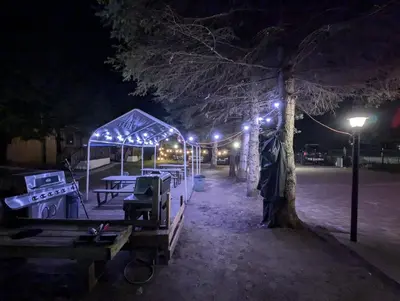 a park lit up at night with tables and a tree at Tiny Wood Cottage 06 in Wasaga Beach