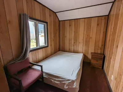 a small room with a bed and a chair at Tiny Wood Cottage 10 in Wasaga Beach