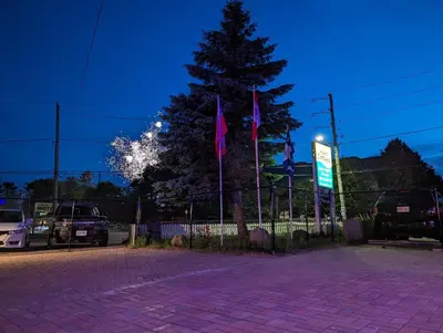 a parking lot with flags and a tree at night at Tiny Wood Cottage 12 in Wasaga Beach