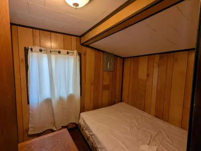 a small room with a bed and a window at Tiny Wood Cottage 15 in Wasaga Beach