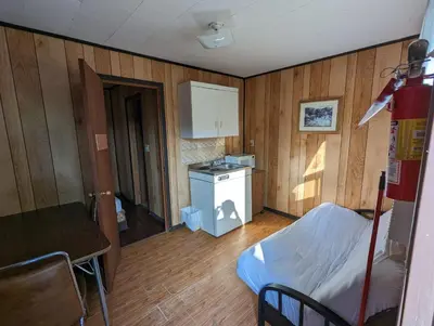 a room with a kitchen with a bed and a table at Tiny Wood Cottage 16 in Wasaga Beach