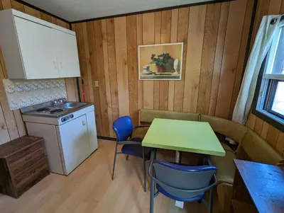 a small kitchen with a table and chairs and a stove at Tiny Wood Cottage 22 in Wasaga Beach