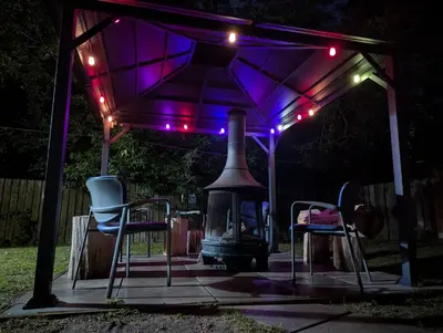 a gazebo with two chairs and a grill with lights at Tiny Wood Cottage 22 in Wasaga Beach